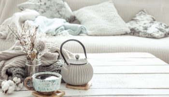 Cozy Scandinavian composition with teapot, ceramic cup of tea and decor details copy space.