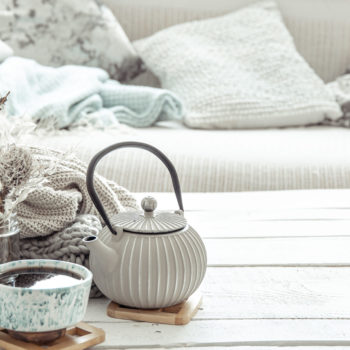 Cozy Scandinavian composition with teapot, ceramic cup of tea and decor details copy space.